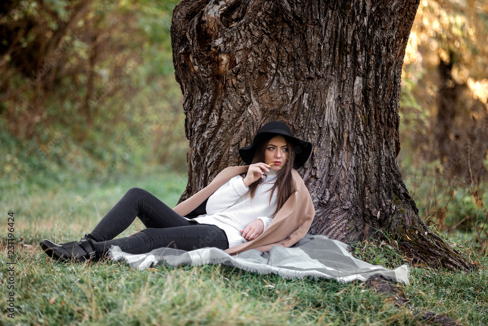 beautiful woman in black hat sitting under big tree beautiful woman in black hat sitting under big tree