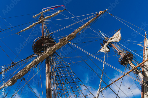 Sailors work with sails at a height on a traditional sailboat