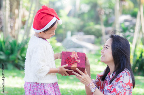 Happy family with mother and daughter holding christmas gift X-mas concept