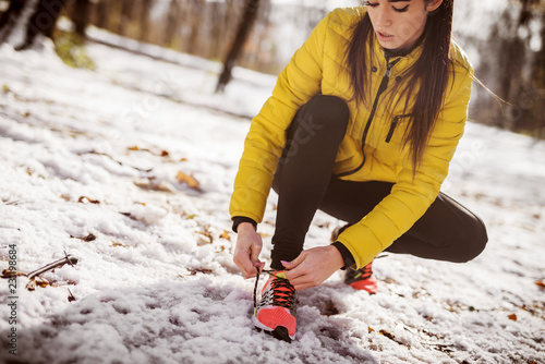 Close up of woman tying shoelace. Training in nature in winter.