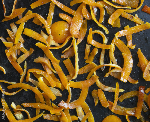 Sliced orange crusts soaked in sugar syrup in a frying pan for making candied fruit for cake