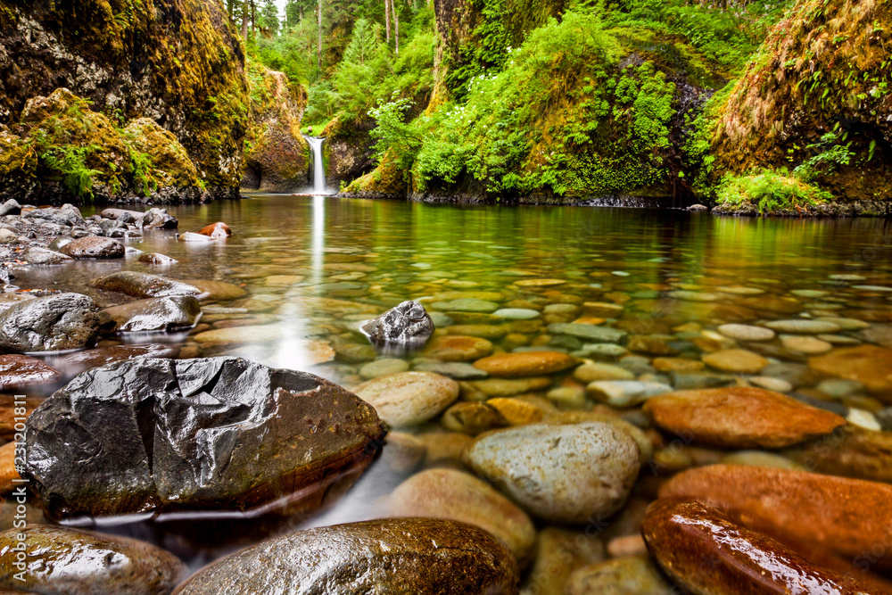 Punch Bowl Falls along the Eagle Creek Trail in Oregon with focus on the rocks in the foreground - obrazy, fototapety, plakaty 