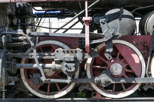 Wheels of the old steam locomotive of red color and the elements of the drive