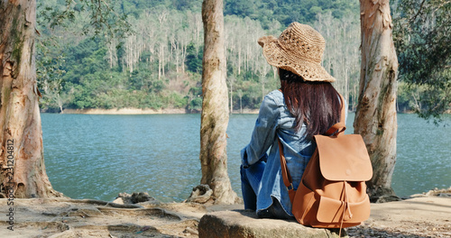 Photography Woman sit on the tree root and enjoy the view of the lake