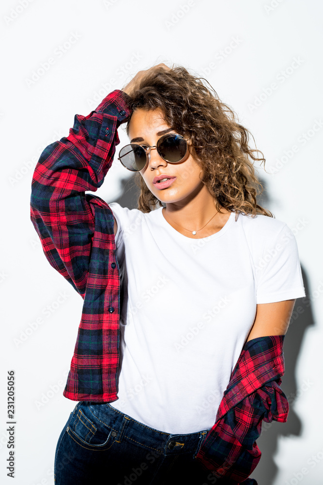 Portrait of curly beautiful latin woman in sunglasses and plaid shirt isolated on white background Portrait of curly beautiful latin woman in sunglasses and plaid shirt isolated on white background