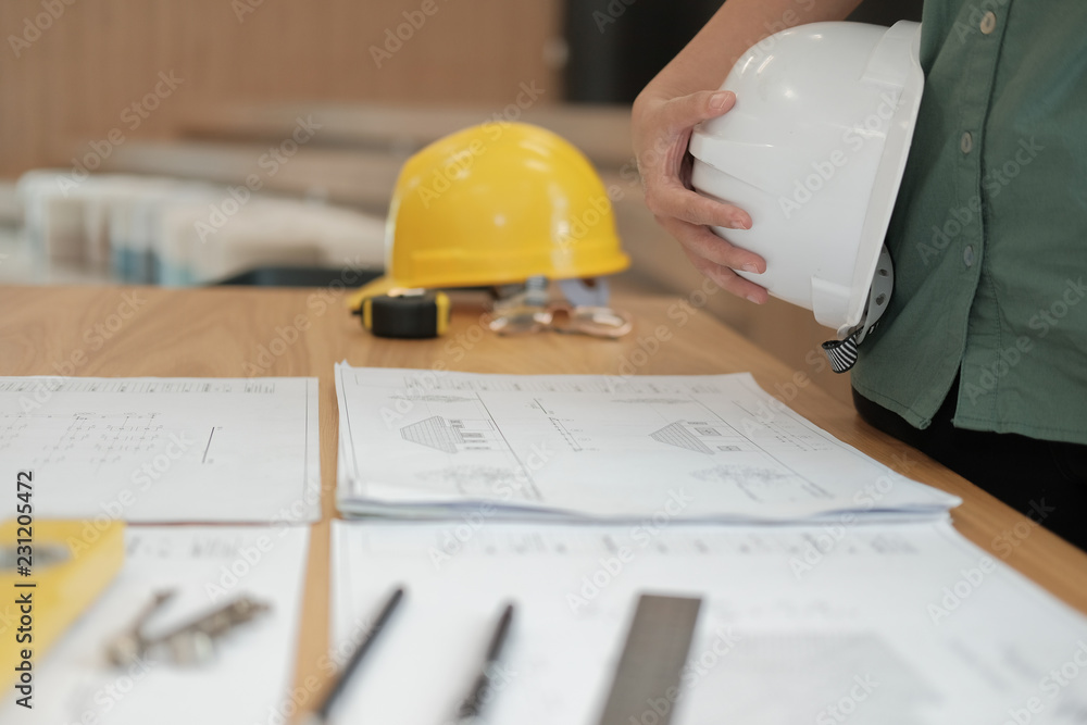 engineer architect worker holding safety helmet hardhat wtih construction blueprint on desk engineer architect worker holding safety helmet hardhat wtih construction blueprint on desk