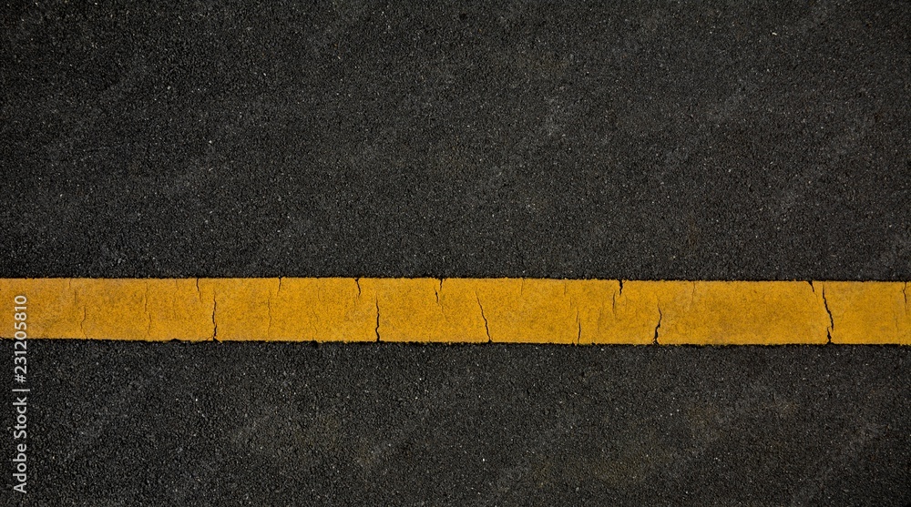 Fototapeta premium Yellow paint line on black asphalt. space transportation background