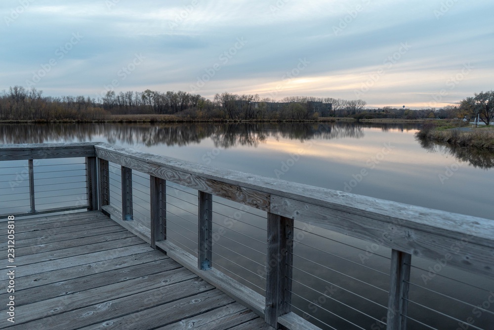 Naklejka premium Dramatic view of still lake water from a wooden dock on a misty Autumn evening