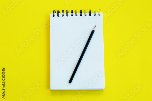 Notebook with pencil on yellow background.