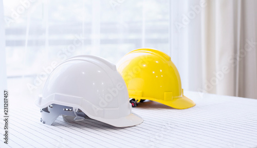 Helmet placed on a white table, White and  yellow hard safety helmet hat for safety project of workman as engineer or worker