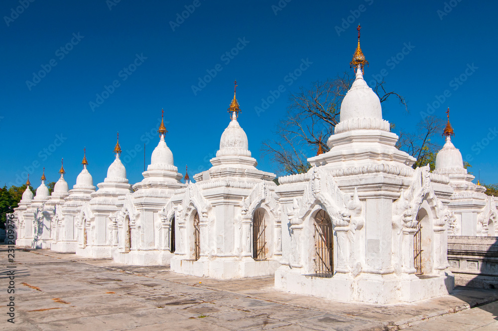 Kuthodaw Pagoda contains the worlds biggest book. There are 729 white stupas with caves with a marble slab inside page with buddhist inscription. Mandalay, Myanmar.
