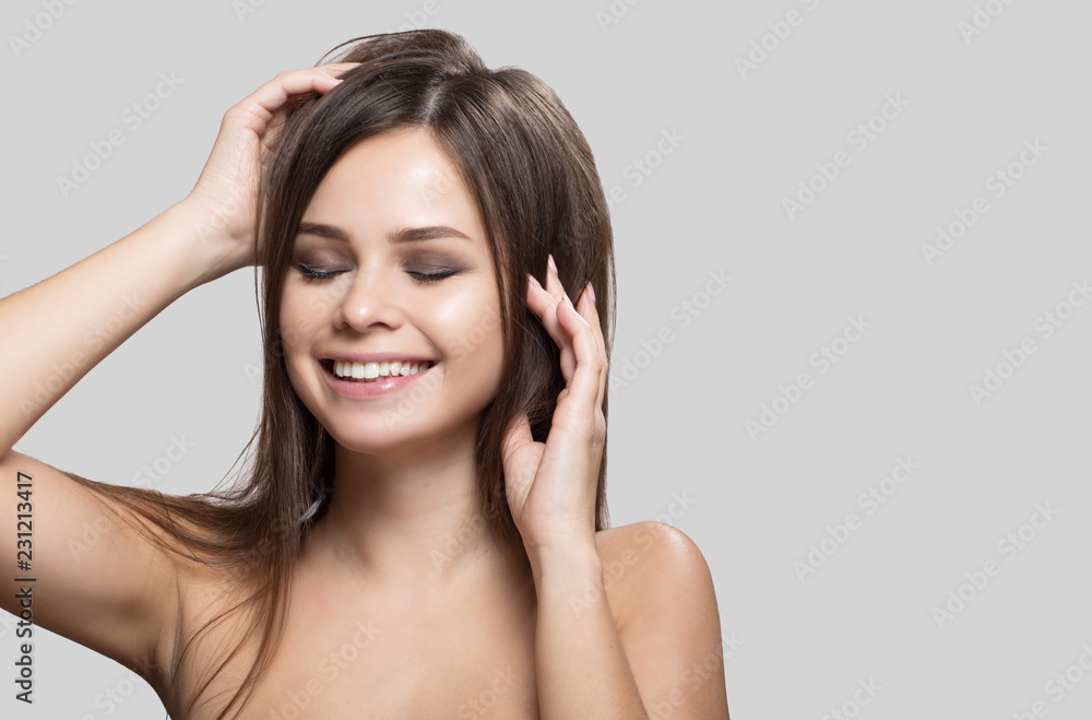 Happy woman with transparent, radiant skin. Face and body skin care. Portrait on a gray background. Touching face Happy woman with transparent, radiant skin. Face and body skin care. Portrait on a gray background. Touching face