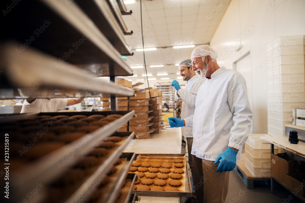 Workers packing cookies in boxes while standing in food factory.