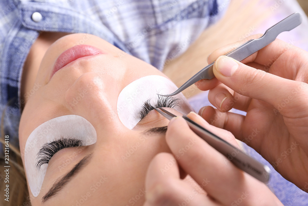 Young woman undergoing eyelash extensions procedure, closeup