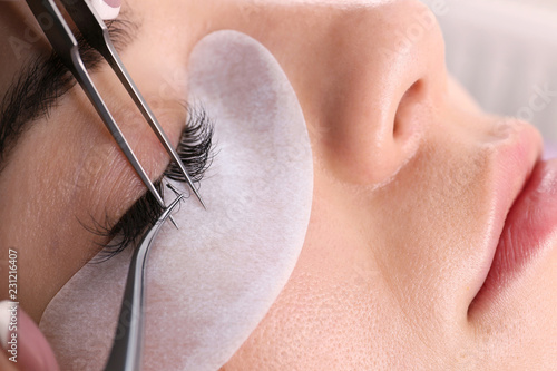 Young woman undergoing eyelash extensions procedure, closeup