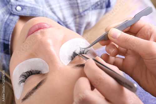 Young woman undergoing eyelash extensions procedure  closeup