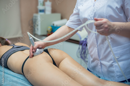 The doctor-cosmetologist performs a vacuum-roll massage of the buttocks and legs of a young woman. Masseuse does her job with the help of the apparatus of correction © Михаил Решетников