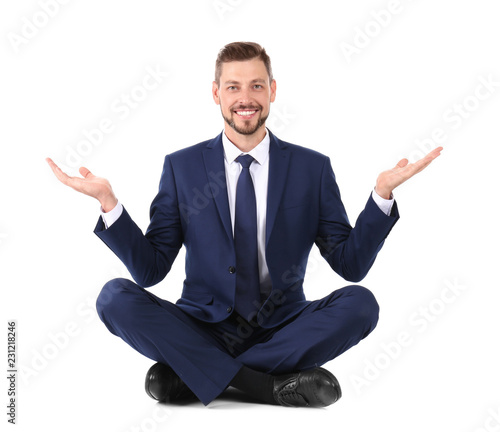 Businessman sitting in lotus position and showing balance gesture on white background © New Africa