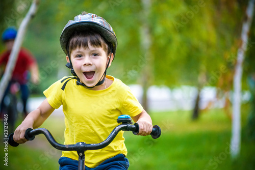 Happy kid boy of 6 years having fun in autumn forest with a bicycle on beautiful fall day. Active child making sports. Safety, sports, leisure with kids concept