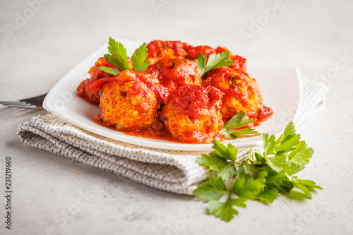 Chicken meatballs with tomato sauce in a white plate.