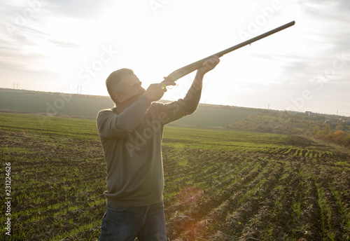 male with old double barreled shotgun is hunting and taking aim