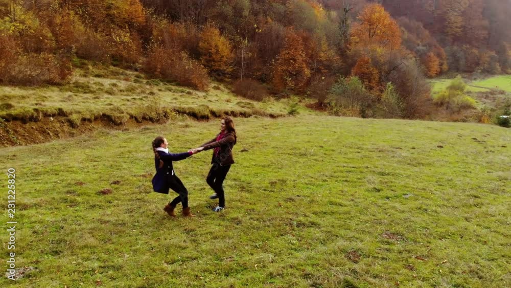 A young mother plays with her little daughter in the autumn forest. Mom and daughter whirl around merrily, holding hands. They are happy. Shooting from the quadcopter A young mother plays with her little daughter in the autumn forest. Mom and daughter whirl around merrily, holding hands. They are happy. Shooting from the quadcopter