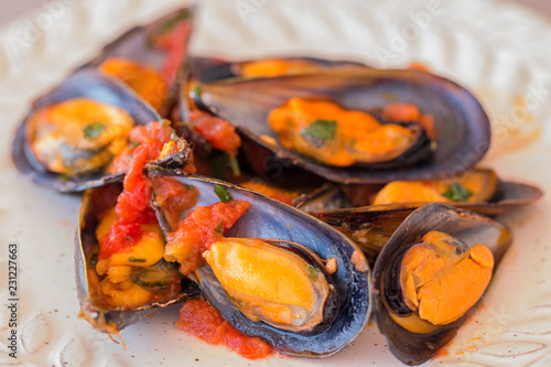 A plate with mussels in tomato sauce.