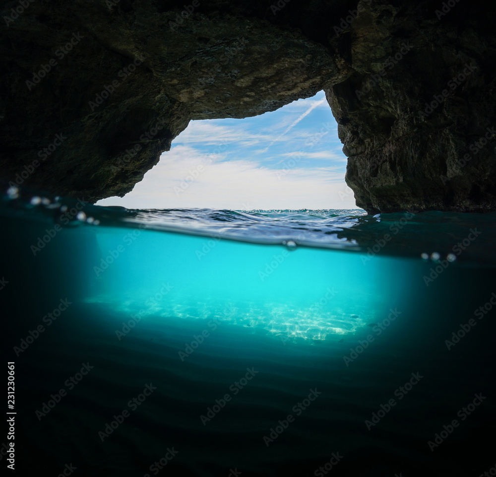 Inside a cave on the seashore with sand underwater, split view half above and below water surface, Mediterranean sea, Spain, Costa Dorada, Cova Del Llop Mari, Tarragona, Catalonia