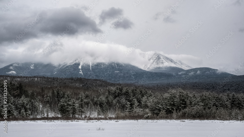 Beautiful winter landscape, mountain in the clouds and snow covered trees. Katahdin, Maine, USA