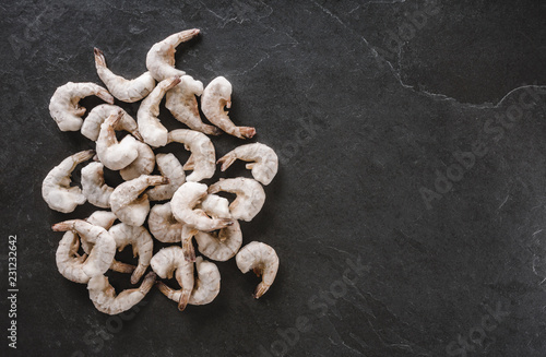 Fresh tiger shrimps or prawn with ice on slate stone background. Seafood, top view, flat lay, copy space