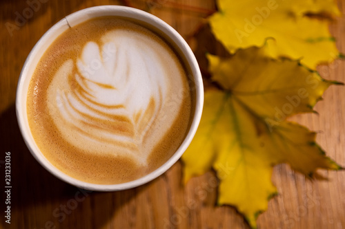 cup of cappuccino with leaves on table