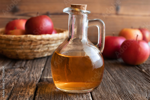 A bottle of apple cider vinegar with fresh apples