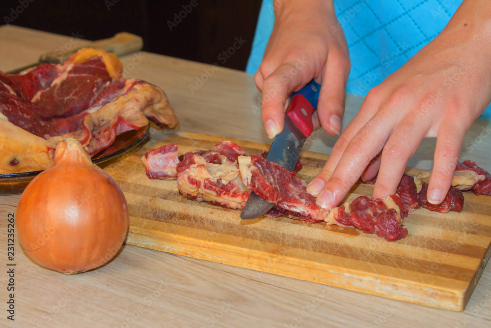 Cook hands with raw meat and vegetables in kitchen