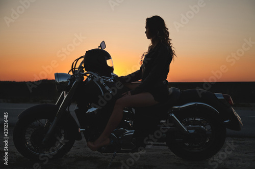 Woman biker at sunset, a trip on a motorcycle, a journey through freedom