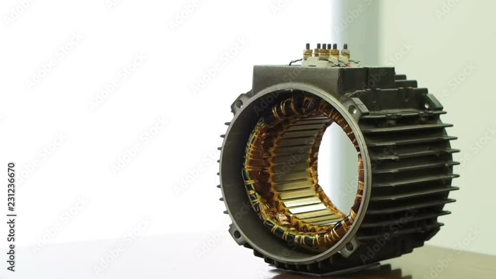 a worker wearing yellow gloves assembles an electric induction motor by ...