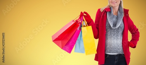 Composite image of blonde in winter clothes holding shopping