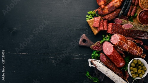 Assortment of salami and snacks. Sausage Fouet, sausages, salami, paperoni. On a black wooden background. Top view. Free space for your text.