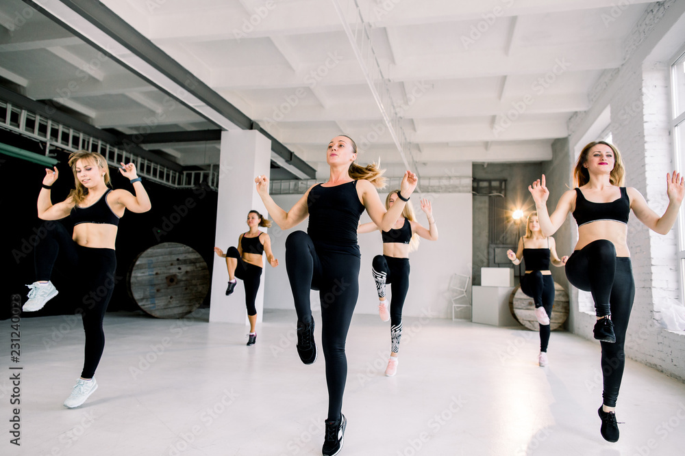 Fototapeta premium Group of sportive people in a gym training - group of athletes stretching before starting a workout session