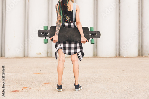 young girl with a longboard on the background of concrete structure