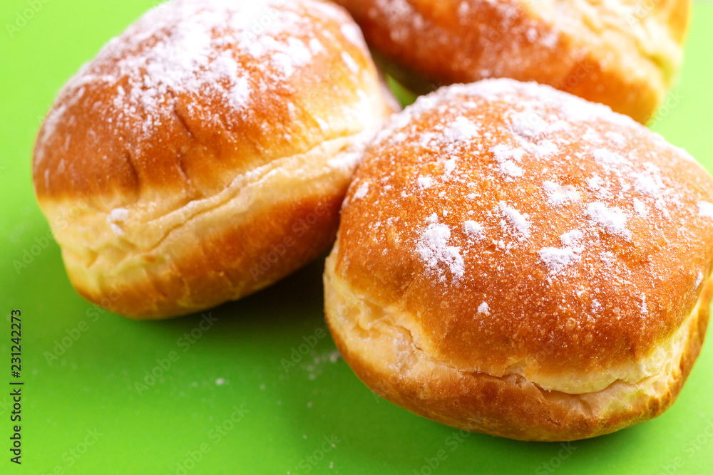 Tasty sweet donuts with powdered sugar on bright green background