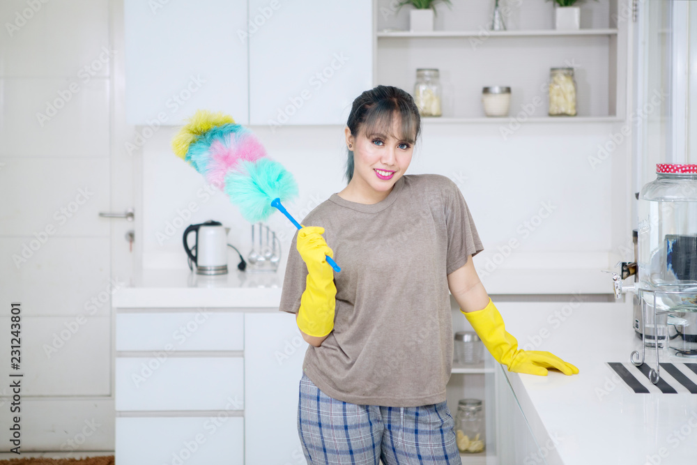 Pretty housekeeper holds duster brush in kitchen Pretty housekeeper holds duster brush in kitchen