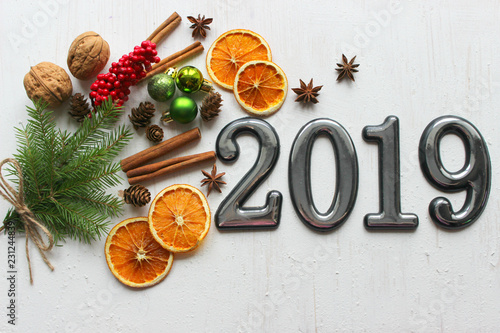 Date 2019 on white wooden background, fir branches, cinnamon sticks and dried orange slices, bokeh effect. 2019 New year.Volume Numbers, dates 2019 on white wooden background, fir-tree branches, bokeh