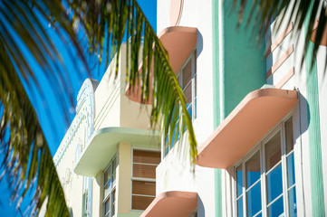 Bright scenic view of colorful pastel details of Art Deco architecture behind palm fronds in South Beach, Miami, Florida