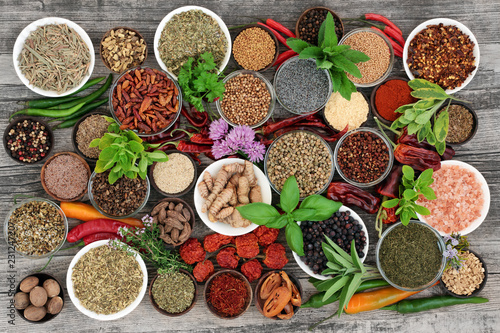 Large herb and spice food selection dried and fresh on rustic wood background. With chilli pepper varieties including dried ring of fire, padron and scorpio. Top view. 