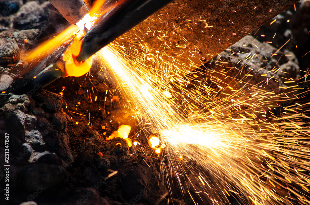 Cutting torch cutting metal bar, flame, hot, sparks with cement