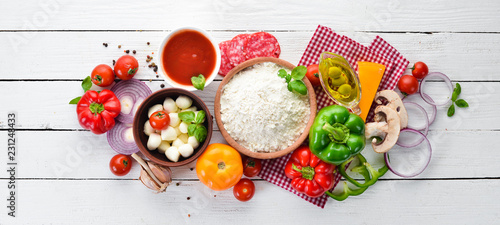 Ingredients for pizza. Mushrooms, sausages, tomatoes, vegetables. Top view. On a white wooden background. Free copy space.