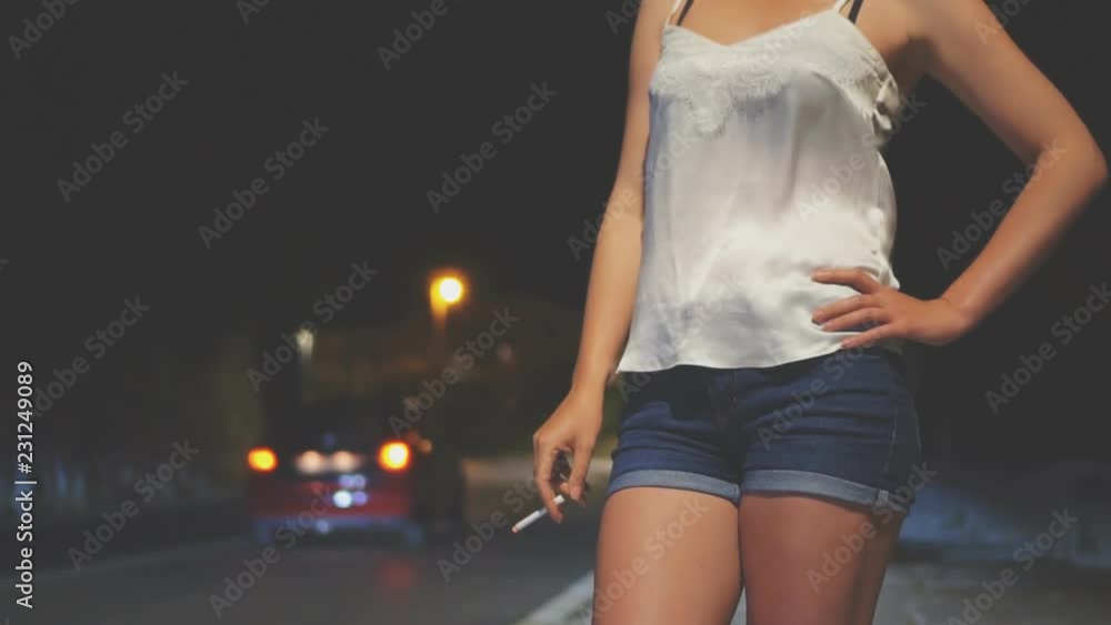 Prostitute with cigarette waiting for the client at night street.