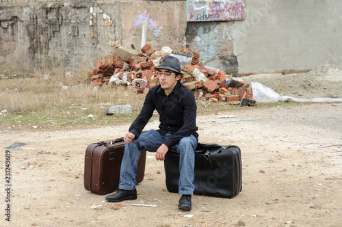 Hombre con sombrero sentado sobre maleta 13