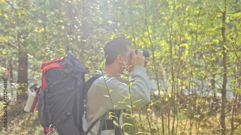 Traveler photographing scenic views in forest by mountain river. Man shooting picturesque views. The guy takes photo and video on old retro camera on film. Professional photographer traveler. Traveler photographing scenic views in forest by mountain river. Man shooting picturesque views. The guy takes photo and video on old retro camera on film. Professional photographer traveler.
