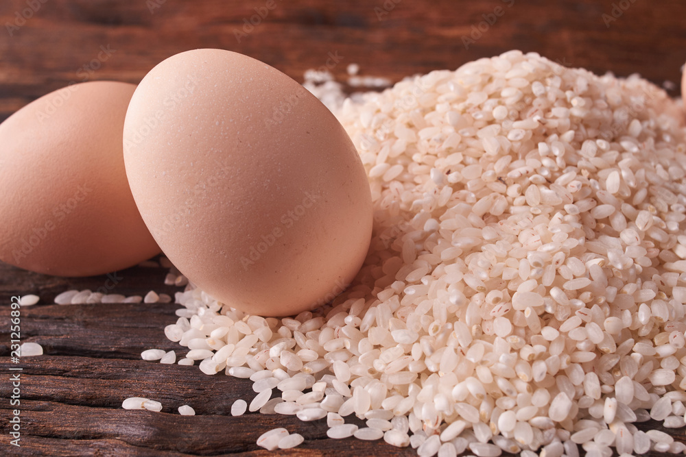 Bunch of rice and uncooced eggs on wooden table. Concept health food Bunch of rice and uncooced eggs on wooden table. Concept health food